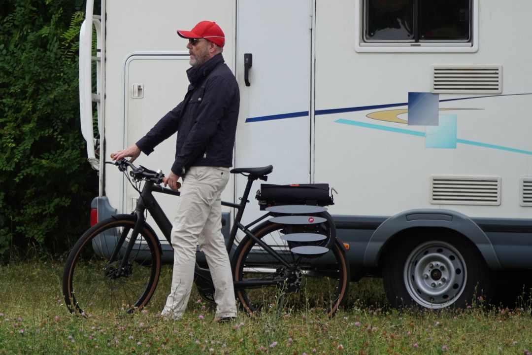 Person mit Fahrrad und gefaltetem Pullit! vor dem Wohnmobil